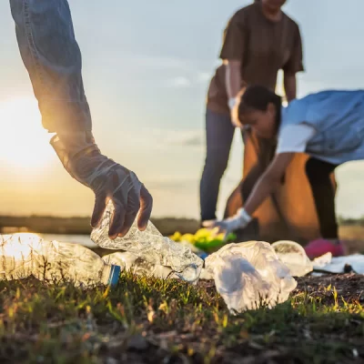 people-volunteer-keeping-garbage-plastic-bottle-into-black-bag-park-near-river-sunset_34152-2042